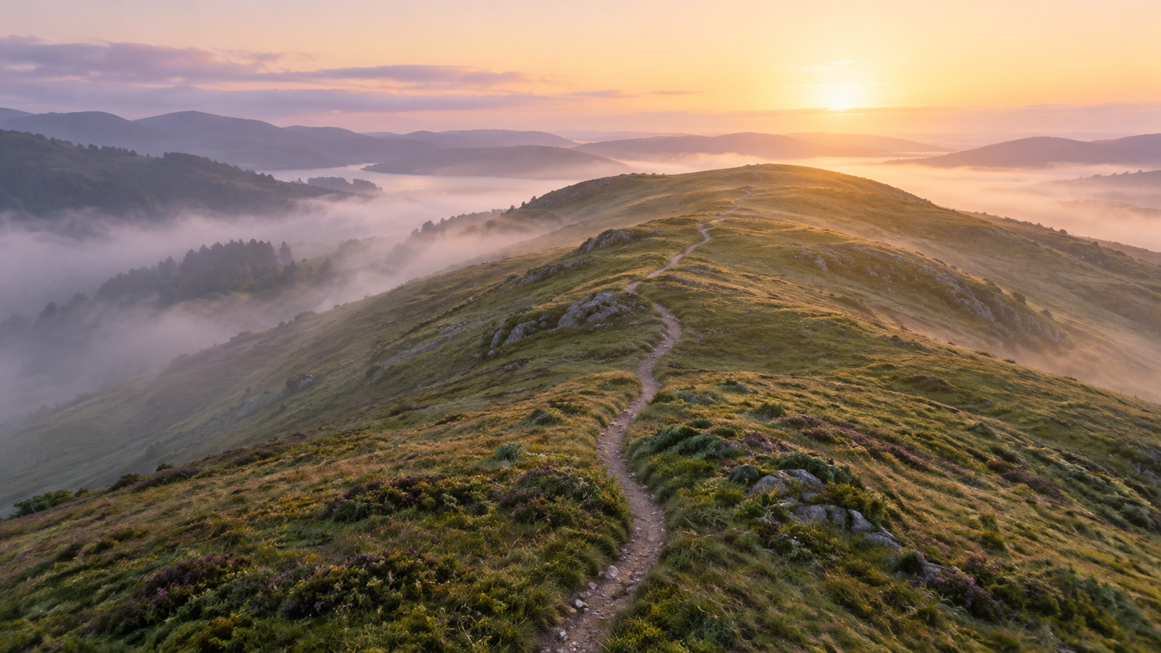 A footpath along a grassy ridge above morning clouds